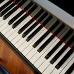 A detailed close-up of piano keys with a wooden floor background, highlighting musical craftsmanship.